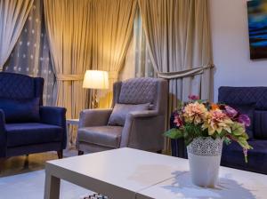 a living room with chairs and a table with a vase of flowers at نزل فلل الريف alreef villas in Baljurashi +14 photos
