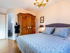 a bedroom with a blue bed and a chandelier at Holiday Home La Lucerie by Interhome in Bretteville-sur-Ay