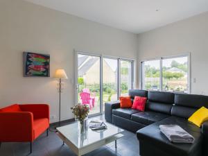 a living room with a black couch and a red chair at Holiday Home Terre et Mer by Interhome in Tréflez +24 photos