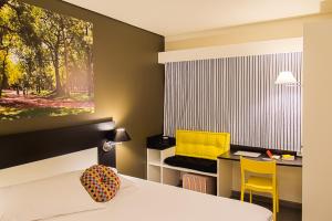 a bedroom with a bed and a desk with a yellow chair at Ibis Styles Porto Alegre Centro in Porto Alegre