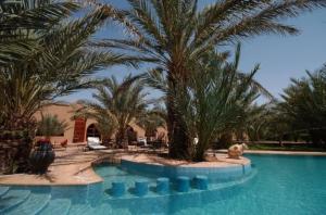 una piscina con palmeras en un resort en La Rose Du Desert, en Erfoud