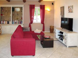 a living room with a red couch and a tv at Holiday Home Sweet Home in Luberon by Interhome in Villelaure