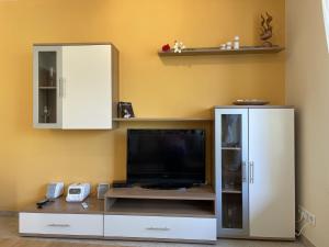 a entertainment center with a flat screen tv and white cabinets at Apartment Müritz Ferienpark Röbel-15 by Interhome in Röbel