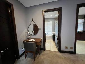 a room with a desk and a mirror and a bathroom at Tredenham Boutique Hotel in Bloemfontein