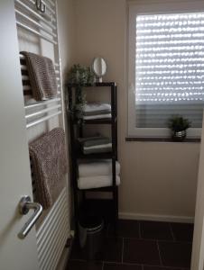 a bathroom with a shelf with towels and a window at Ferienwohnung Marita in Rietberg +20 photos