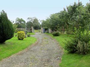 a gravel road in a garden with bushes and trees at Holiday Home Les Lutins by Interhome in Commes
