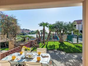 a table and chairs on a patio with a view of a yard at Apartment Le Margherite - SLR264 by Interhome in Costarainera