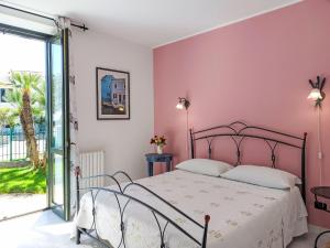 a bedroom with a bed with a pink wall at Apartment Le Margherite - SLR264 by Interhome in Costarainera