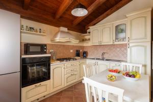 a kitchen with white cabinets and a table with a bowl of fruit at Sant'Antioco - Spazioso appartamento al centro in SantʼAntìoco