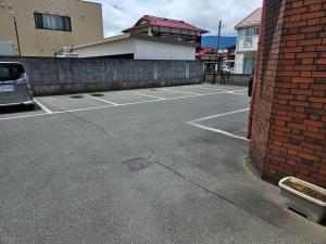 a parking lot with a building and a red brick wall at Plaza Inn Kawaguchiko in Fujikawaguchiko