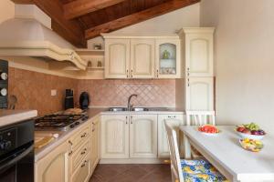a kitchen with white cabinets and a sink at Sant'Antioco - Spazioso appartamento al centro in SantʼAntìoco +16 photos