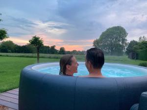 a man and a woman sitting in a hot tub at Cour 44 - Gite de charme avec sauna et jacuzzi in Remicourt