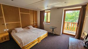a bedroom with a bed and a window and a table at Mala Narnia in Frymburk