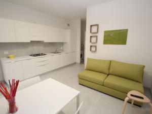 a living room with a green couch and a kitchen at Apartment Marcello-7 by Interhome in Rosolina Mare