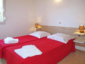 a bedroom with two beds with red sheets and white towels at Apartment Grand app- RDC- 6 pers- by Interhome in Calvi