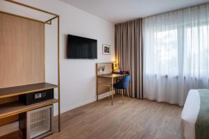 ブリュッセルにあるJill Hotel Brusselsのベッド、テレビ、デスクが備わるホテルルームです。