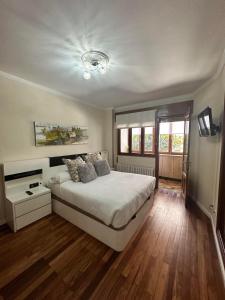 ein Schlafzimmer mit einem großen weißen Bett und Holzböden in der Unterkunft Alojamiento en el corazón de Monforte de Lemos en Ribeira Sacra in Monforte de Lemos