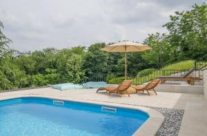 una piscina con due sedie e un ombrellone di Peaceful Villa with Pool & Sauna, La Casa di Kyra a Brajkovići