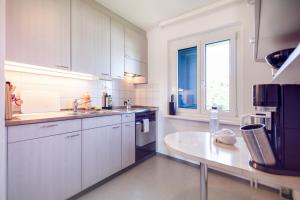 een keuken met witte kasten en een groot raam bij all you need - 20 Minutes to Mainstation - own room in shared flat in Unterengstringen