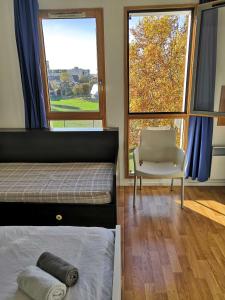 een slaapkamer met een bed, een stoel en ramen bij Studio lumineux 10 min à La Défense 2 in Rueil-Malmaison