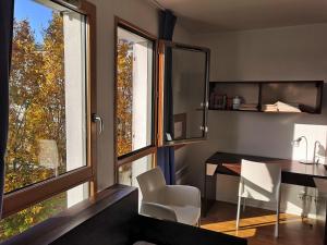 een eetkamer met een tafel, stoelen en ramen bij Studio lumineux 10 min à La Défense 2 in Rueil-Malmaison