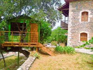 a tree house in a yard next to a building at Arcadianis Villa at Psari Trikolonon Gortynia in Psárion