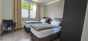 two beds in a room with a chair and a window at Gästehaus Orchidee in Hoya