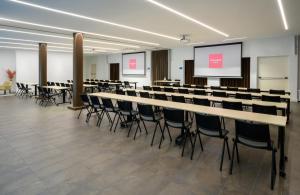 una sala conferenze con tavoli, sedie e schermo di Leonardo Hotel Lago di Garda - Wellness and Spa a Lazise