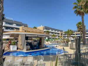 a swimming pool with chairs and a bar in a resort at Aloha Flamenca in Orihuela