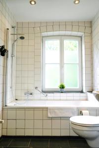 a bathroom with a tub and a toilet and a window at Stilvolles Apartment in stadtnähe-Parkplatz- 4 Personen- Balkon in Wolfsburg +8 photos