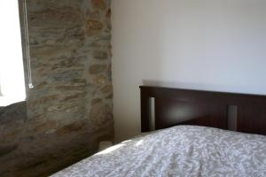une chambre avec un lit et un mur en pierre dans l'établissement Casa Escola Velha, à Vale de Cameiro