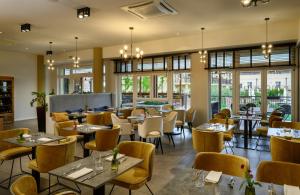um restaurante com mesas, cadeiras e janelas em Leonardo Hotel Lago di Garda - Wellness and Spa em Lazise