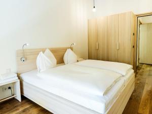ミッテルベルクにあるalpen select apartments Kleinwalsertalの白いシーツが敷かれた大きなベッドのある寝室