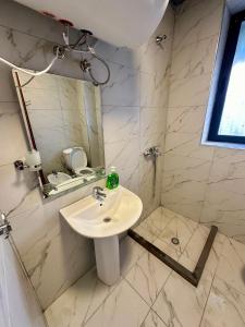 a white bathroom with a sink and a mirror at Krid Tirana Studio Flat in Tirana +7 photos