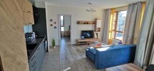a living room with a blue couch and a kitchen at Aх, морето in Burgas