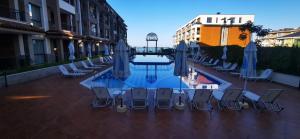 a pool with chairs and umbrellas on a patio at Aх, морето in Burgas