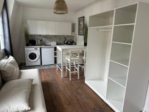 kuchnia z białymi szafkami i stołem z krzesłami w obiekcie Sceaux - Locations de Charme dans Maison w mieście Sceaux