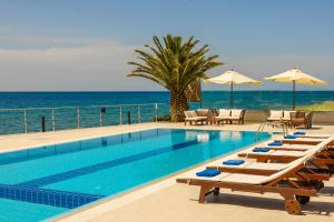 a swimming pool with chairs and umbrellas next to the ocean at Niki Beach Hotel in Kamariotissa
