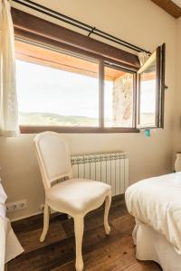 a white chair in a bedroom with a window at Casa Rural Herencia de Ganaderos "Sierra de Gredos- Ávila" in San Martín de la Vega del Alberche