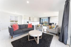 a living room with a couch and two chairs and a table at The Sandpiper- Pet and Family Friendly in Goolwa South