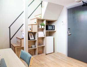 a room with a table and a refrigerator and a staircase at Habyt Studios Kallang in Singapore