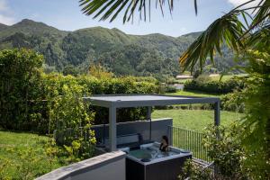 a woman sitting in a hot tub in a garden at Casa nas Caldeiras in Furnas