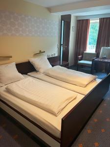 Vintagehotel Adler في باد بيتريتش: سريرين في غرفة الفندق مع كرسي