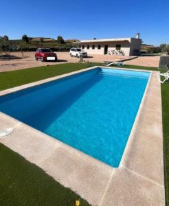 a blue swimming pool in a yard with a parking lot at Cabezo Buñuel alojamiento Rural in Calanda