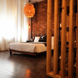 1 dormitorio con cama y pared de ladrillo en Maison Évangéline by Bower Boutique Hotels en Moncton