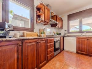 Una cocina grande con gabinetes de madera y ventanas. en Villa Alicia by Interhome, en L'Ampolla