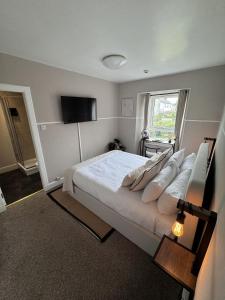 a bedroom with a large bed and a television at The Glendevon Hotel in Auchterarder