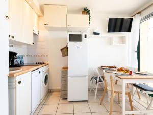 a kitchen with a white refrigerator and a table at Apartment Cap Océan-8 by Interhome in Mimizan