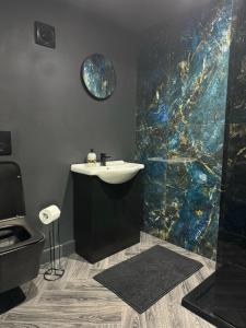 a bathroom with a sink and a mosaic wall at Eco House 1 in Prestatyn