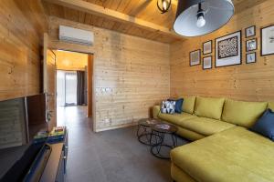 a living room with a green couch and wooden walls at Drvena bajka Ville za odmor Magnolia i Kamelia in Bilje